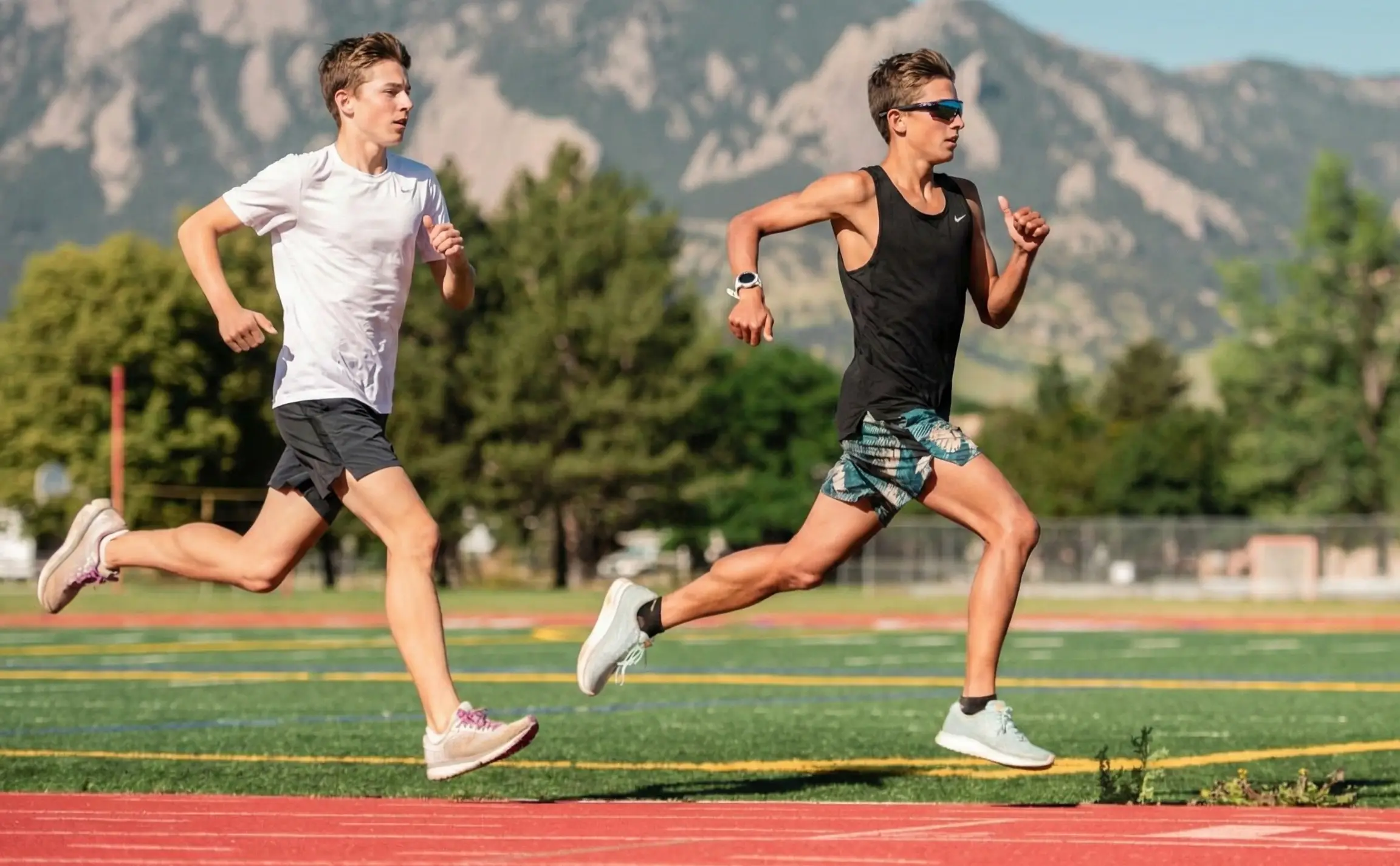 two boys running a hard workout on the track