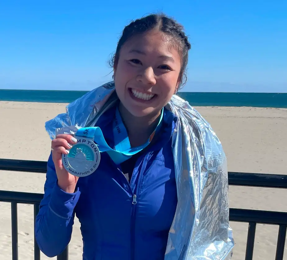Runner celebrating with a finisher medal at the beach after a race